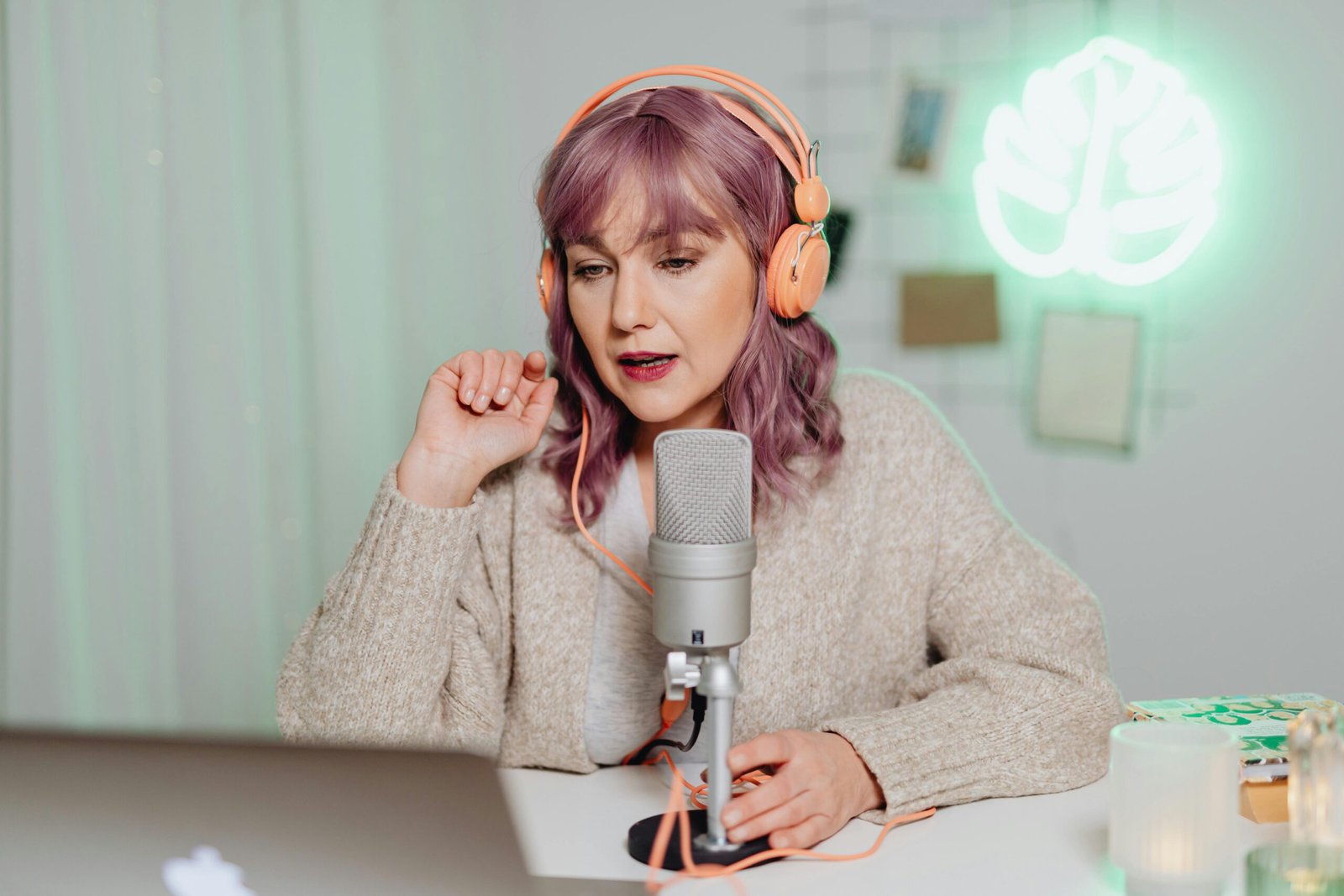 Woman podcaster in a cozy room speaking into a microphone, wearing headphones.